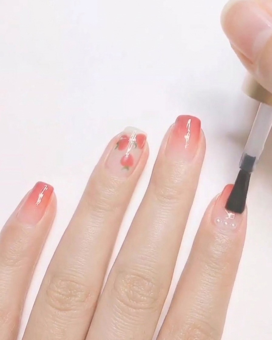 Un pennello per unghie applica un top coat trasparente su un design per unghie finito con piccole perle incapsulate.