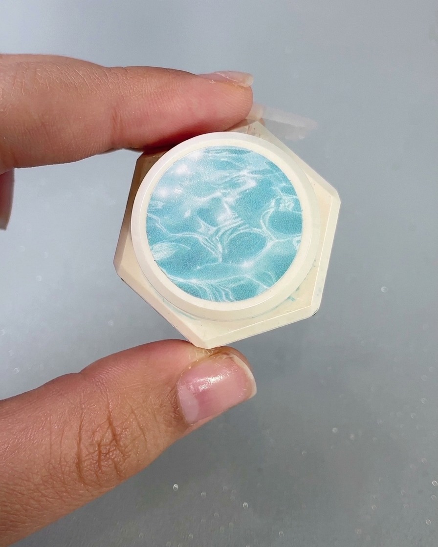 Un contenitore che mostra il gel vetro ad alta trasparenza con un motivo a increspature dacqua sulletichetta.