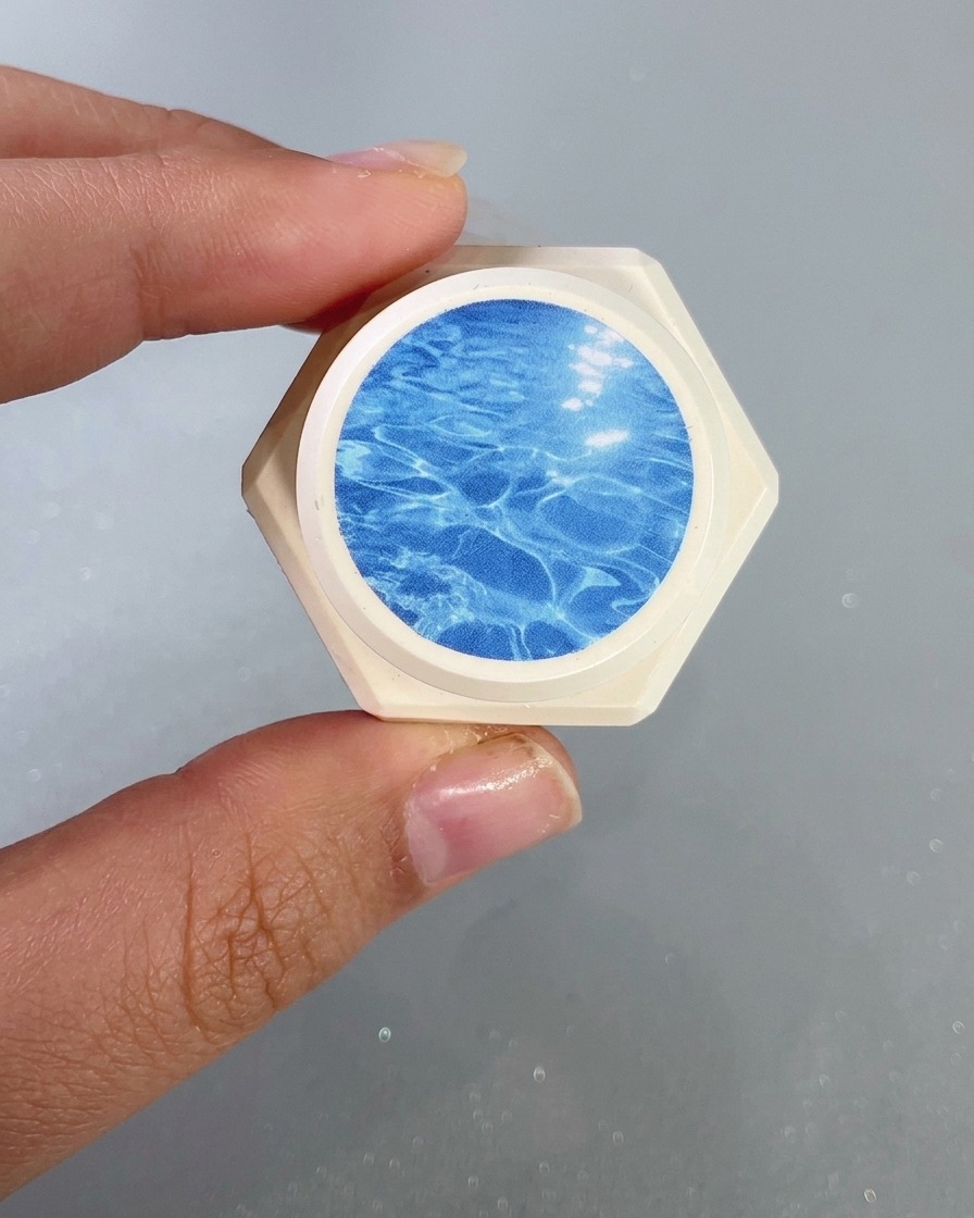 Un primo piano di un pennello per unghie che applica un gel vetro blu trasparente sulla punta dellunghia.