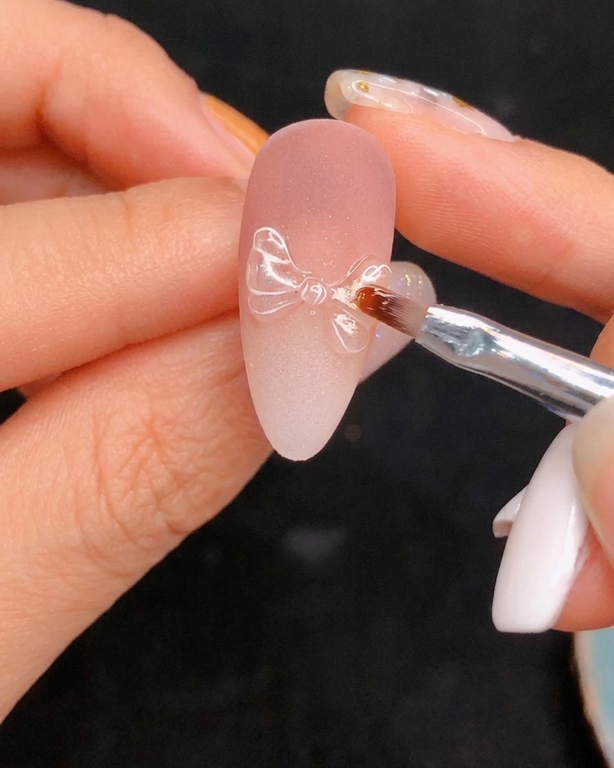 Applicazione del top coat lucido finale sopra la nail art dettagliata.