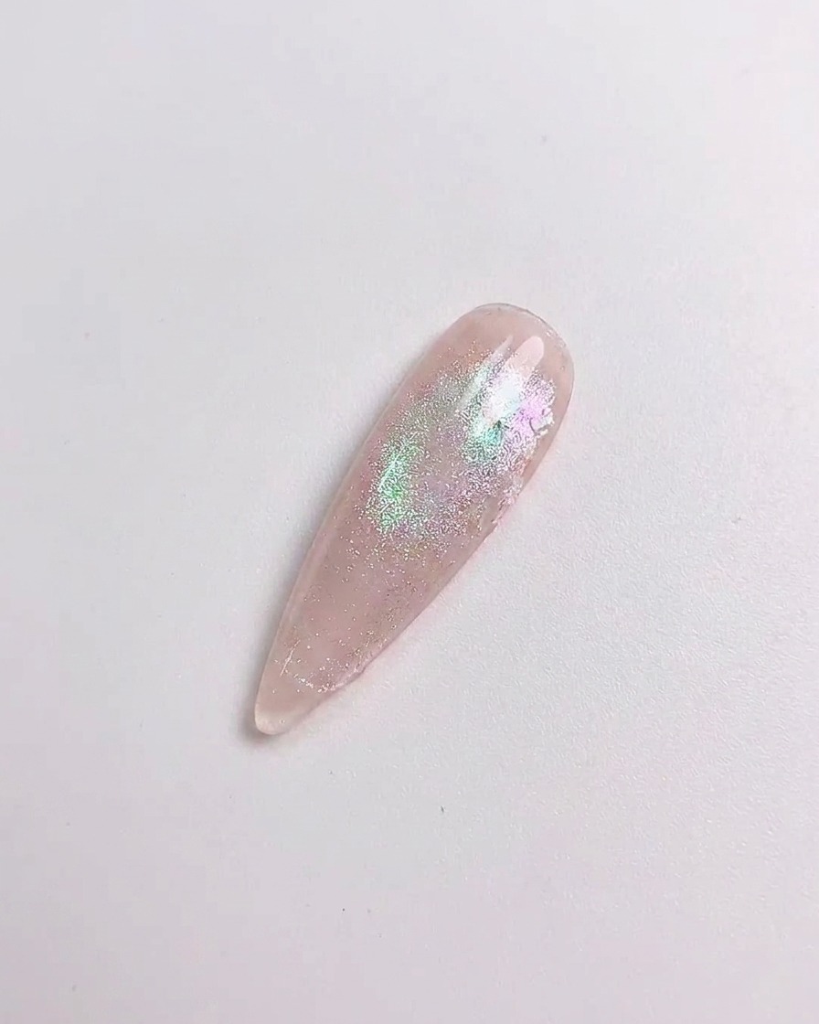 Uno strumento in silicone sfrega la polvere aurora sulla superficie polimerizzata dellunghia.