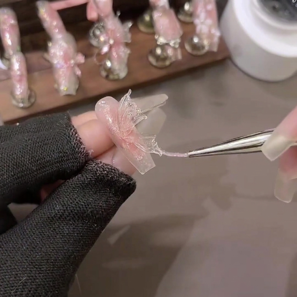 Un pennello da scultura modella un triangolo di gel in PVC formando ali di farfalla dettagliate su carta da supporto.