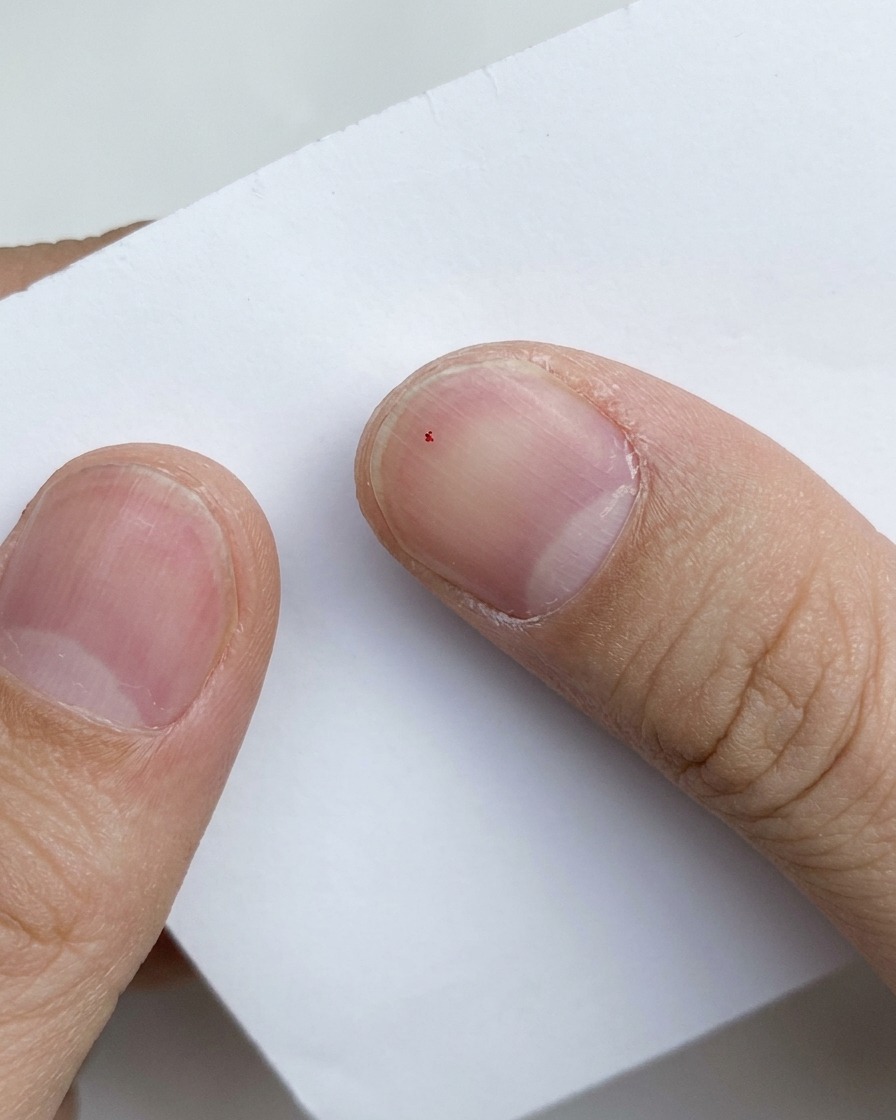 Primo piano di un minuscolo granello di glitter viola mescolato su uno sfondo di carta bianca.