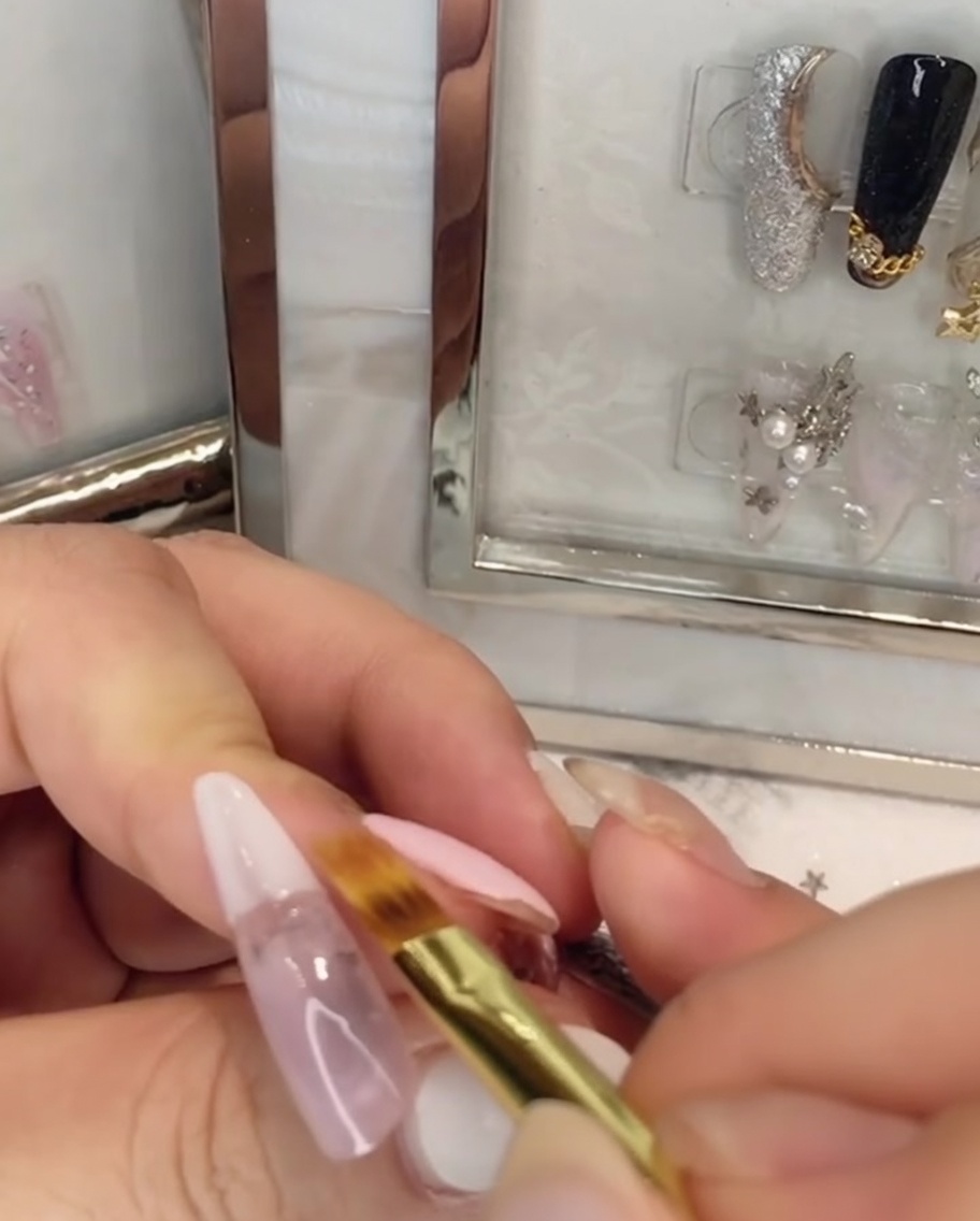 Un pennello piatto che sfuma lo smalto gel bianco verso lalto nel gel rosa sullunghia.
