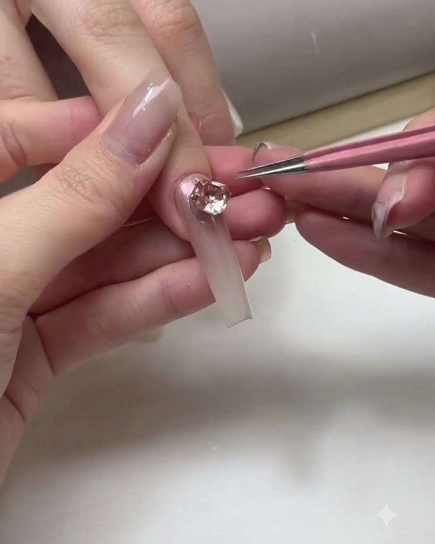 Una onicotecnica che applica uno strato di top coat trasparente sulla superficie di unghie ombré completate.