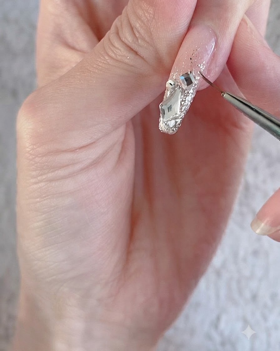 Un pennello liner fine che delinea grandi strass di cristallo scintillanti e ciondoli su una superficie ungueale decorata.