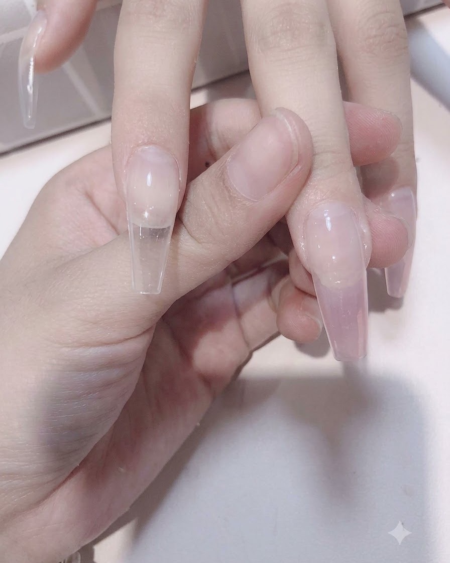 Un pennello da unghie sfuma il gel rosa trasparente verso il basso sopra unestensione trasparente per creare un effetto sfumato.