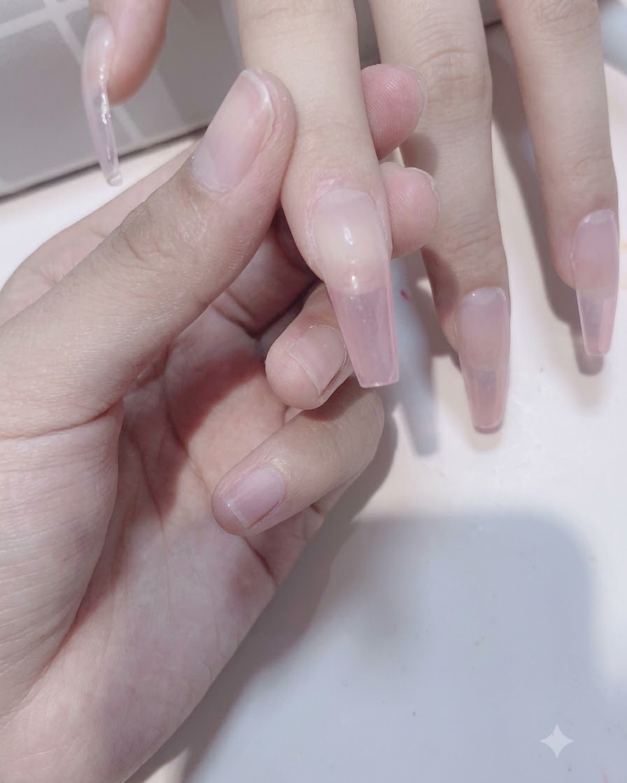 Primo piano di dita che mostrano la seconda applicazione di gel rosa trasparente per aumentare la profondità della sfumatura.
