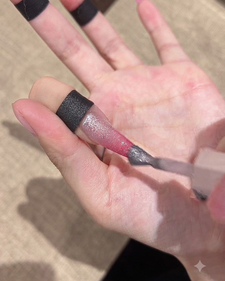 Un pennello applica un gel cat-eye brillante sulla superficie dellunghia sfumata.