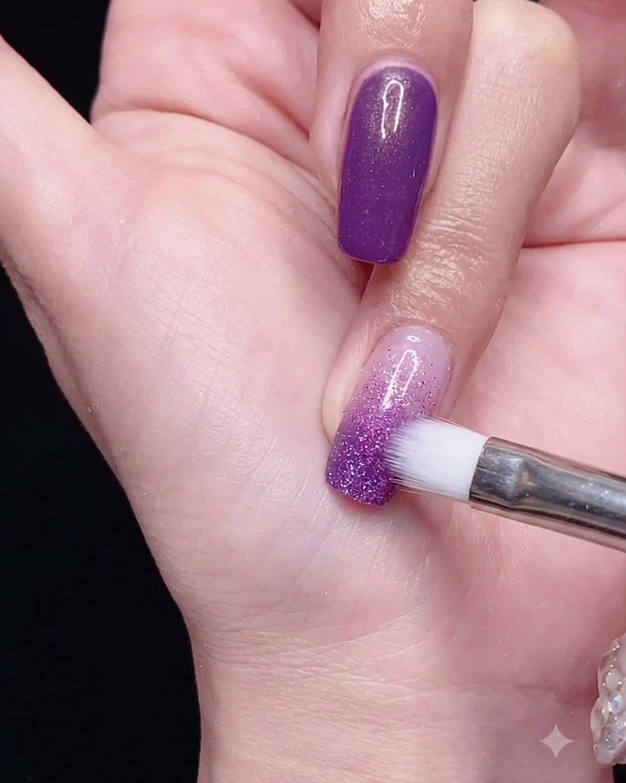 Un pennello per sfumature che lavora lo smalto gel viola verso il basso per un morbido effetto ombré.