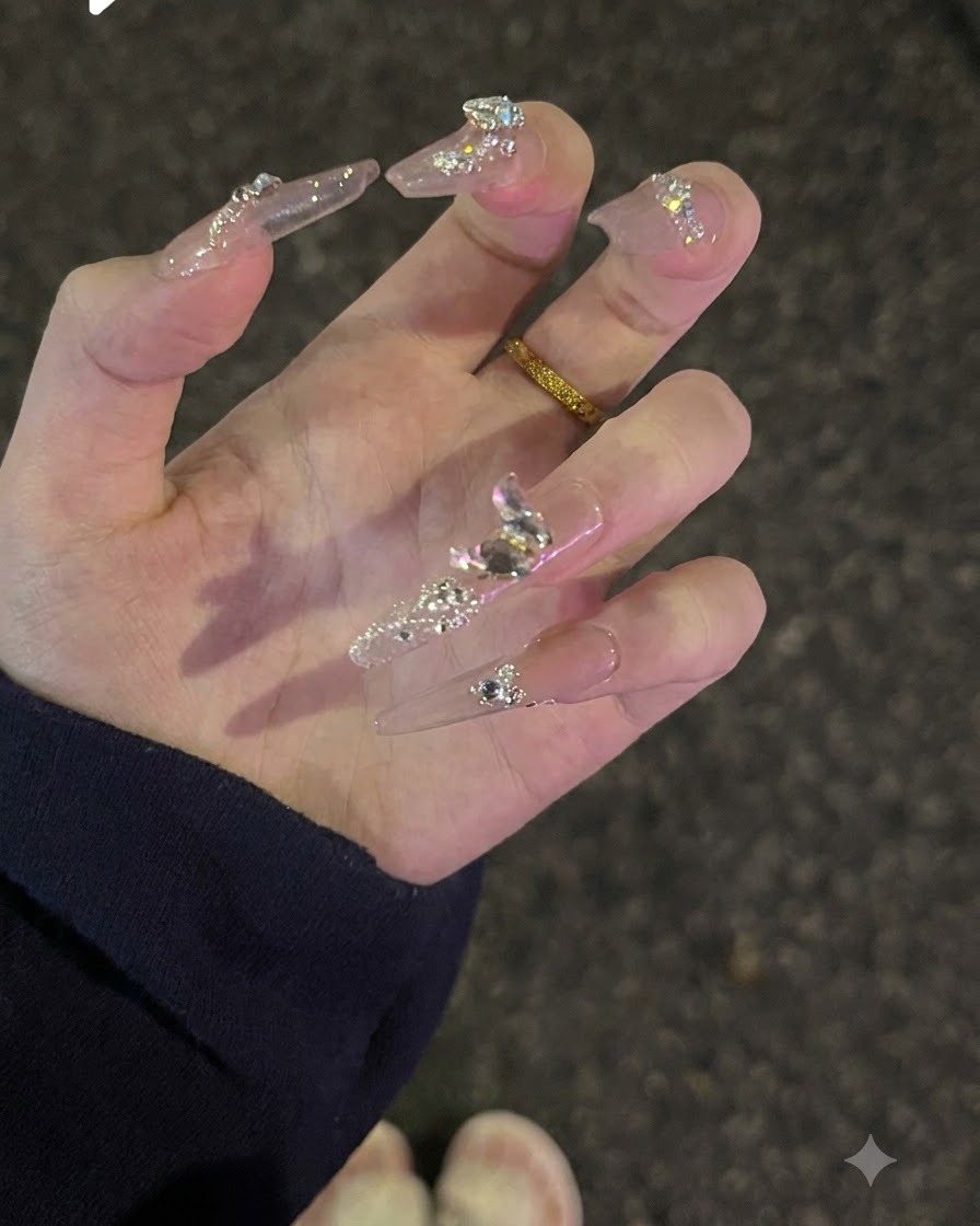 Una mano girata verso lalto per mostrare i glitter sulla superficie superiore e i cristalli di diamante scintillanti su unghie nude.