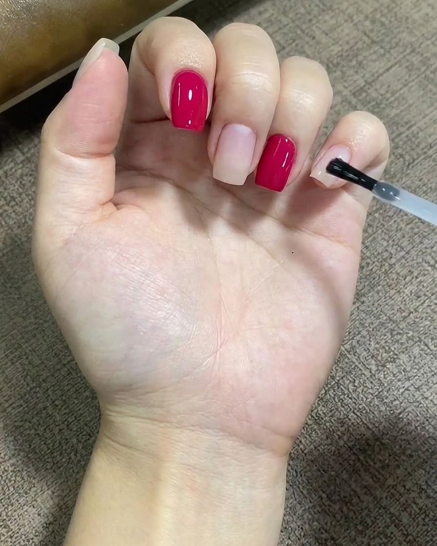 Un pennello applica uno strato trasparente di base coat in modo uniforme sulla superficie di ununghia.