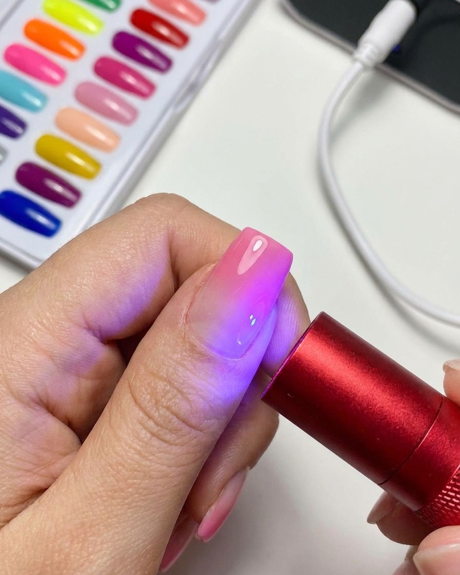 Una lampada UV/LED portatile rossa che illumina ununghia in gel cat-eye magnetico finita.