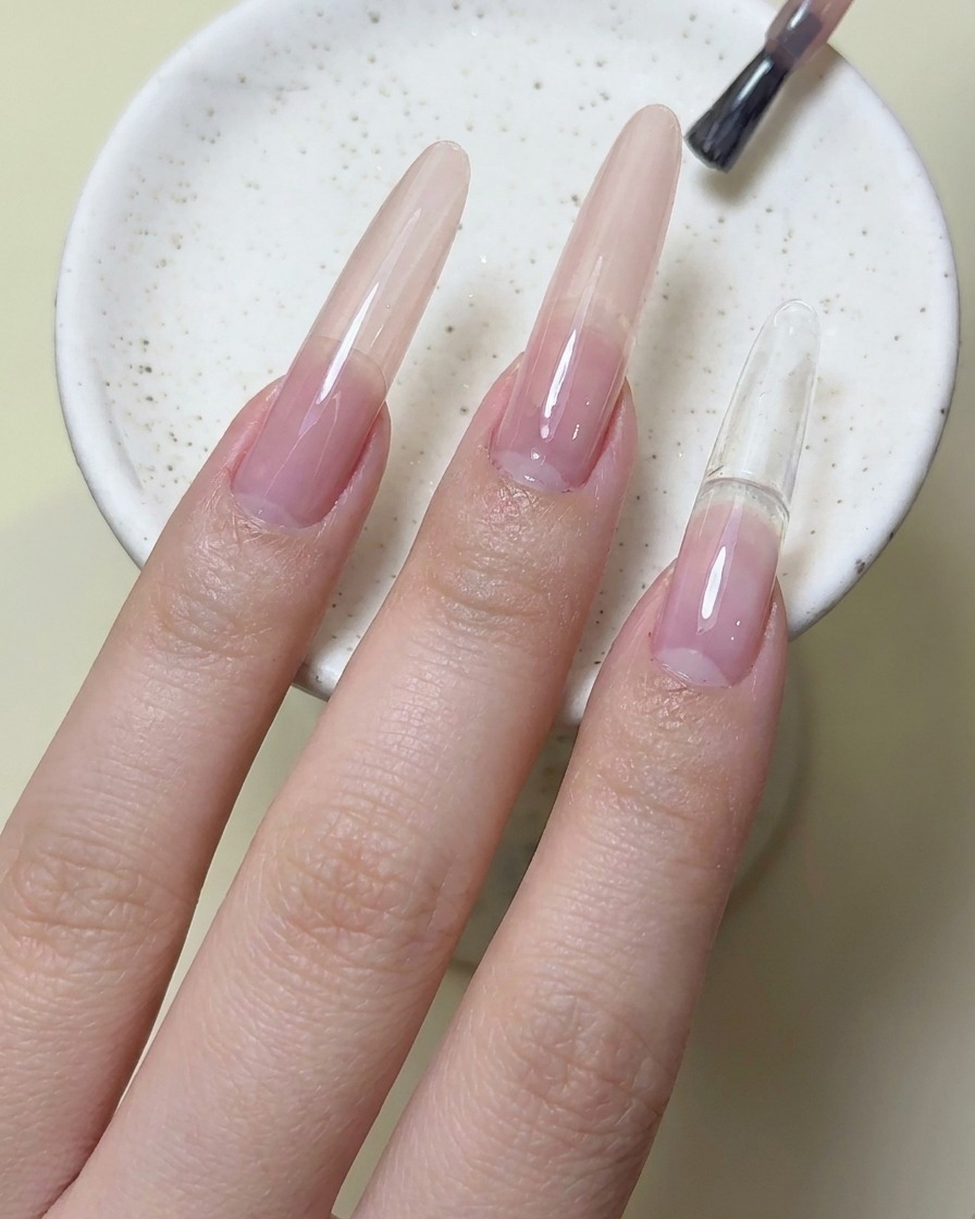 Un pennello applica lo smalto gel rosso magenta sullunghia del dito indice.