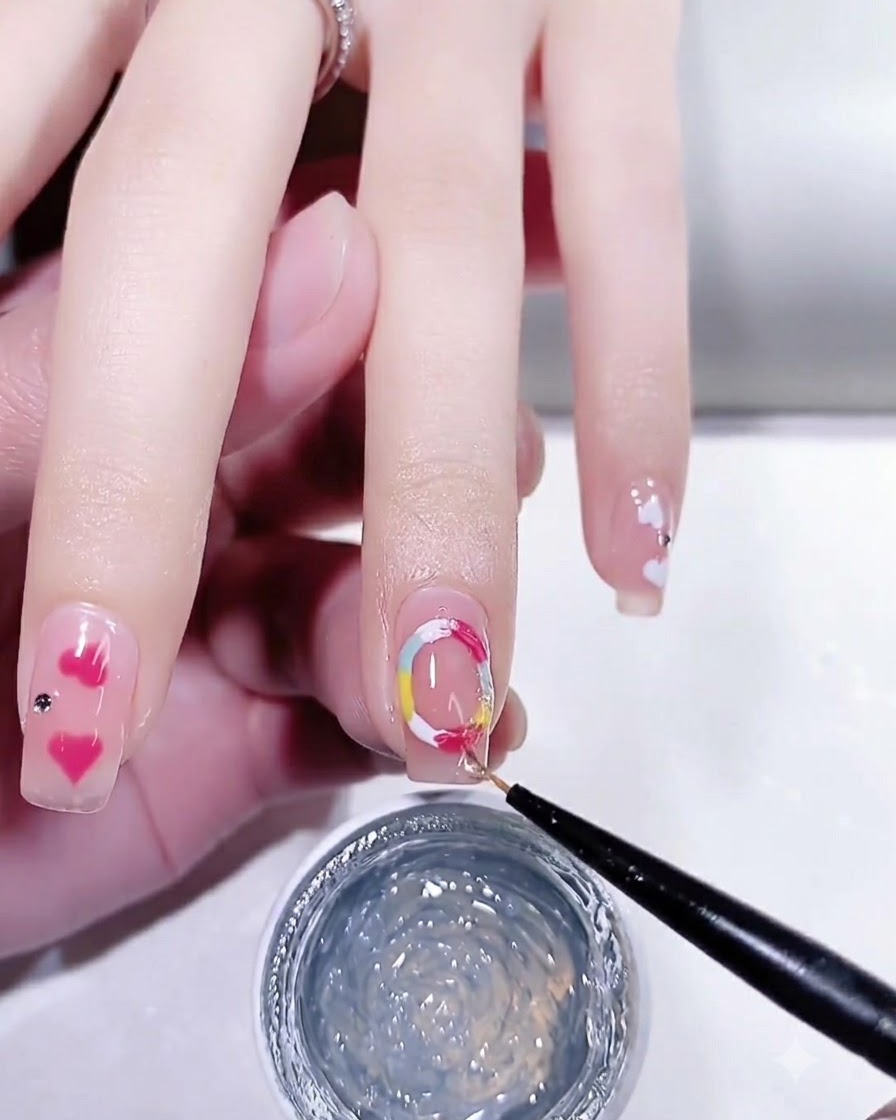 Un pennello fine per nail art che applica un top coat lucido su ununghia curata con dettagli a punti colorati.