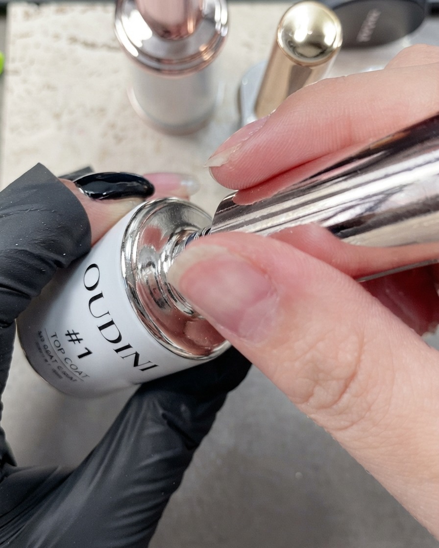 Una vista ravvicinata di un pennello fine che applica il top coat lungo il bordo di ununghia dellindice manicure.