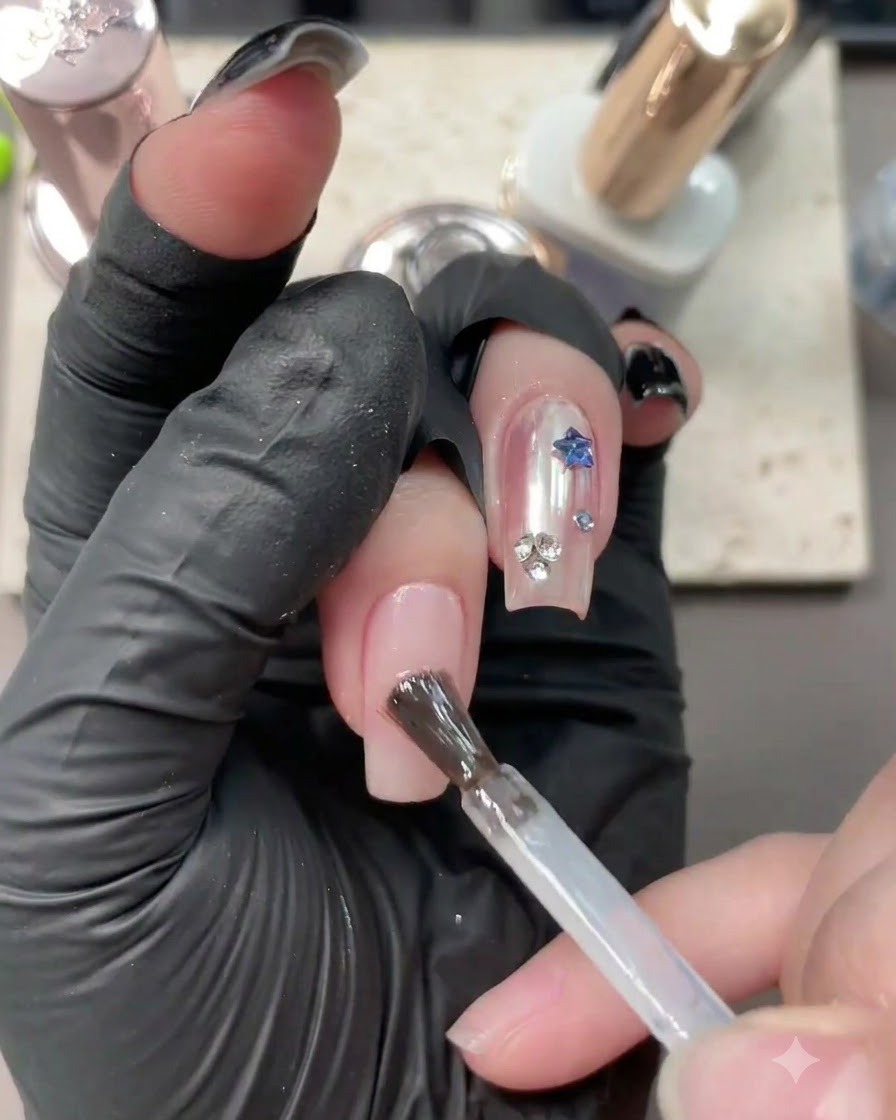 Un pennello che applica il gel base trasparente su ununghia nude neutra con nail art esistente.