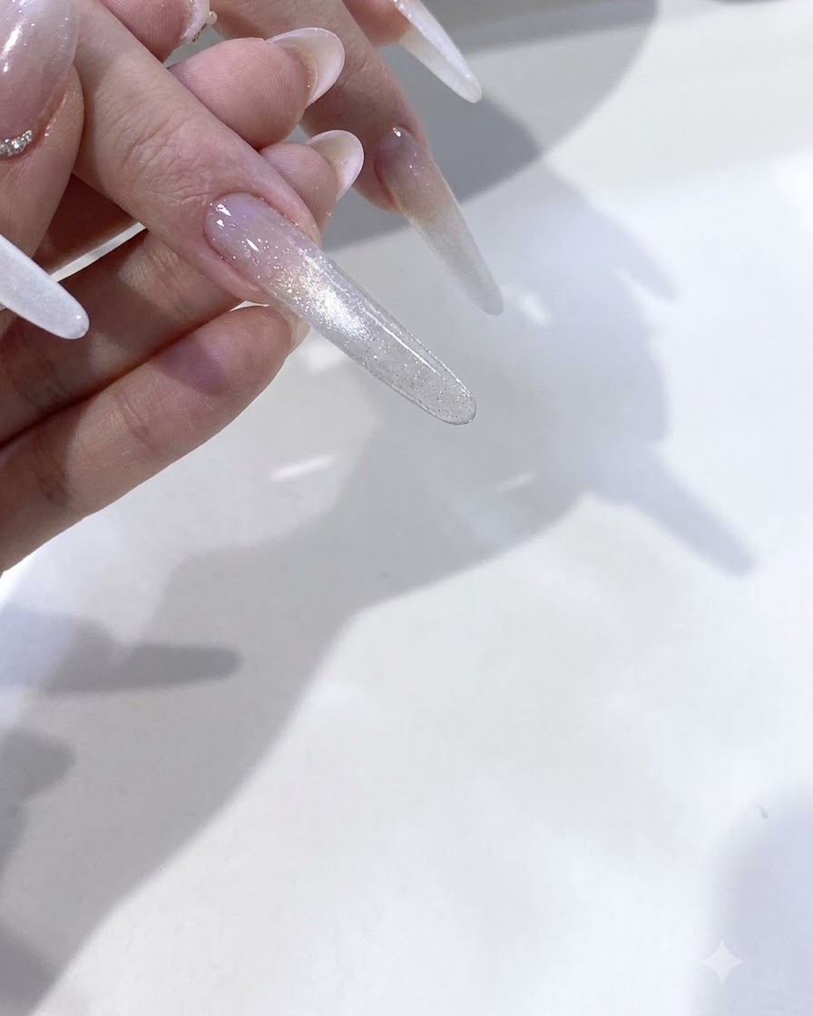 Dita in fase di polimerizzazione sotto il bagliore rosa di una lampada per unghie UV/LED.