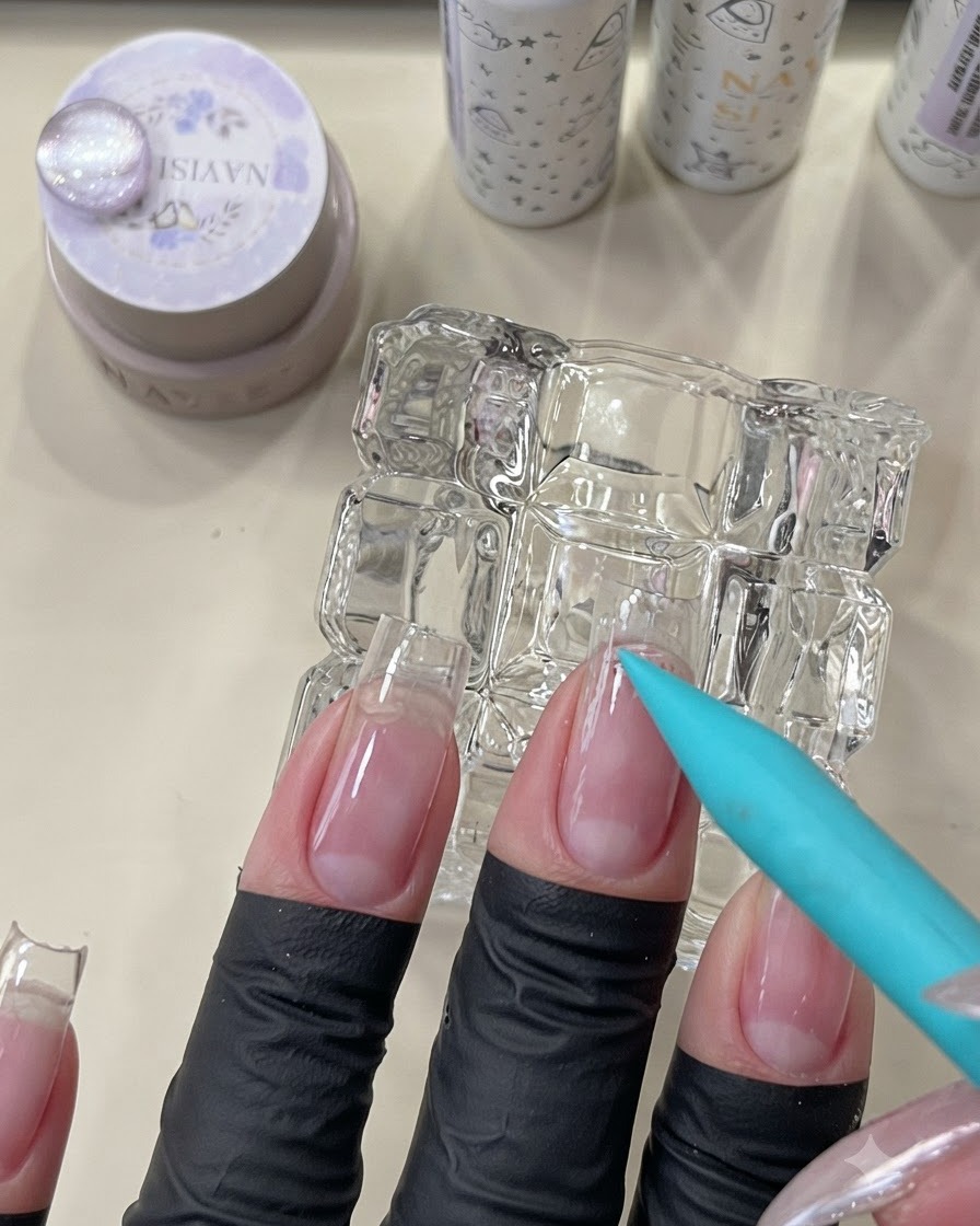 Un pennello blu che applica una base trasparente peel-off nella zona delle cuticole di ununghia naturale.