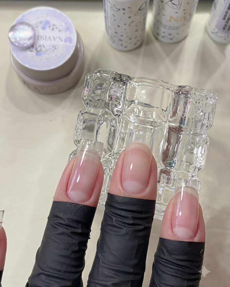Dita posizionate sotto una mini lampada UV/LED per polimerizzare lo strato di base.