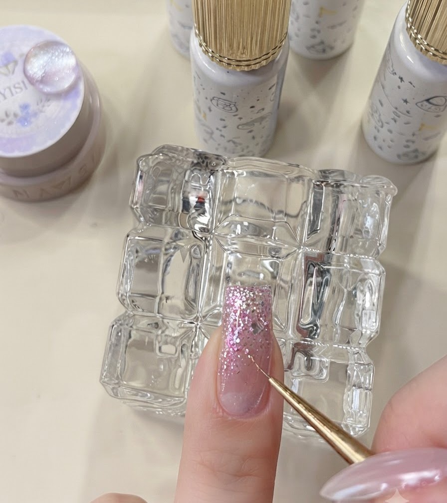 Uno strumento di dettaglio che posiziona fiocchi a stella su ununghia con glitter non polimerizzati.