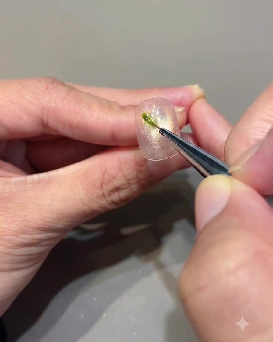 Un pennello a punta fine che applica un piccolo tratto verticale di gel verde avocado su ununghia cat eye.