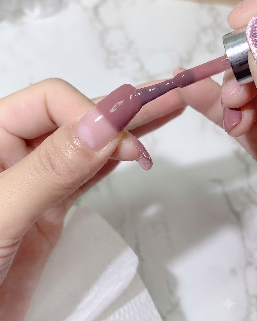 Un pennello che applica una seconda mano di gel colorato sullunghia per intensificare la tonalità sfumata.