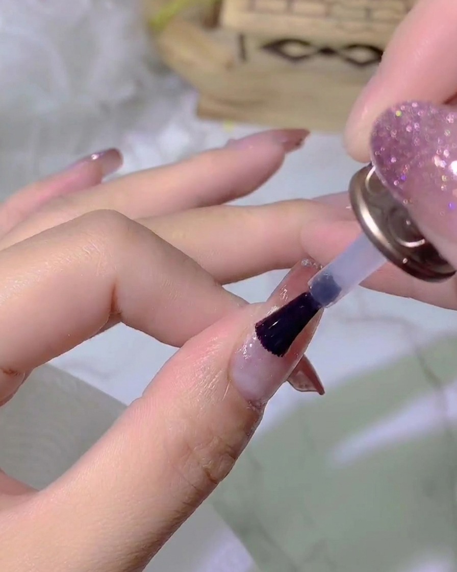 Una mano inserita sotto una lampada per unghie UV/LED che polimerizza lo strato di top coat.