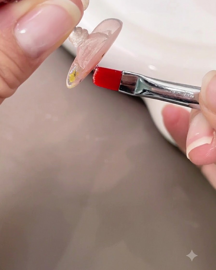 Una mano che tiene ununghia capovolta mentre usa un pennellino per controllare lapice del gel costruttore trasparente autolivellante.