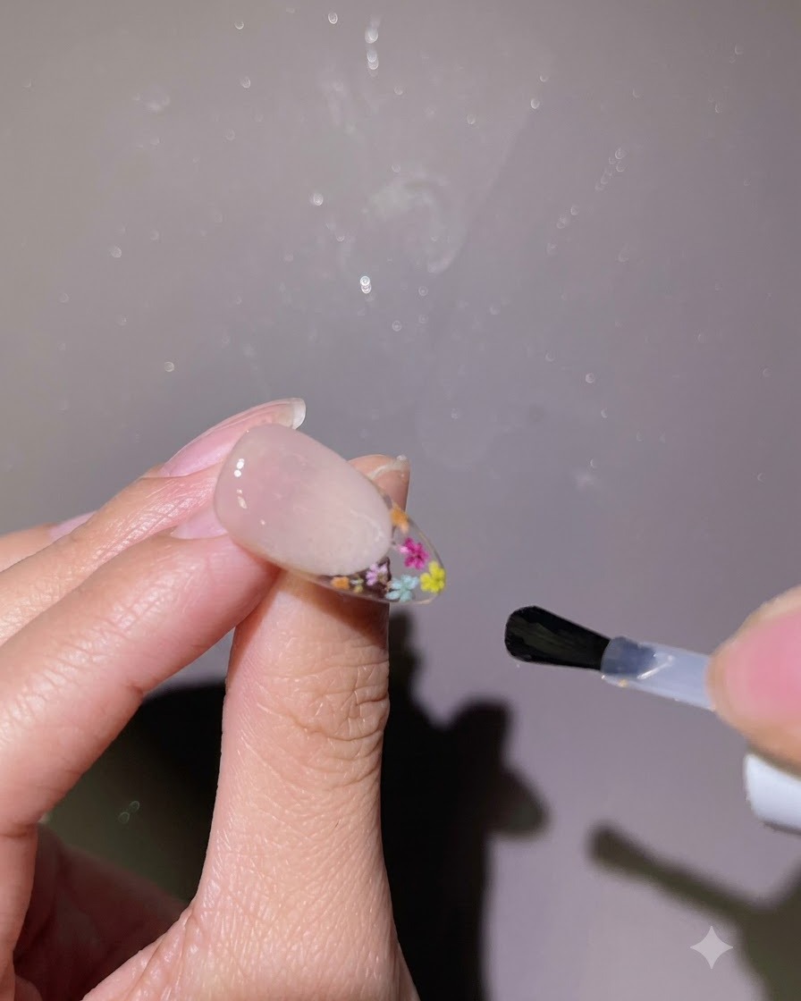 Un pennello che applica un top coat lucido sullintera superficie di ununghia finita.
