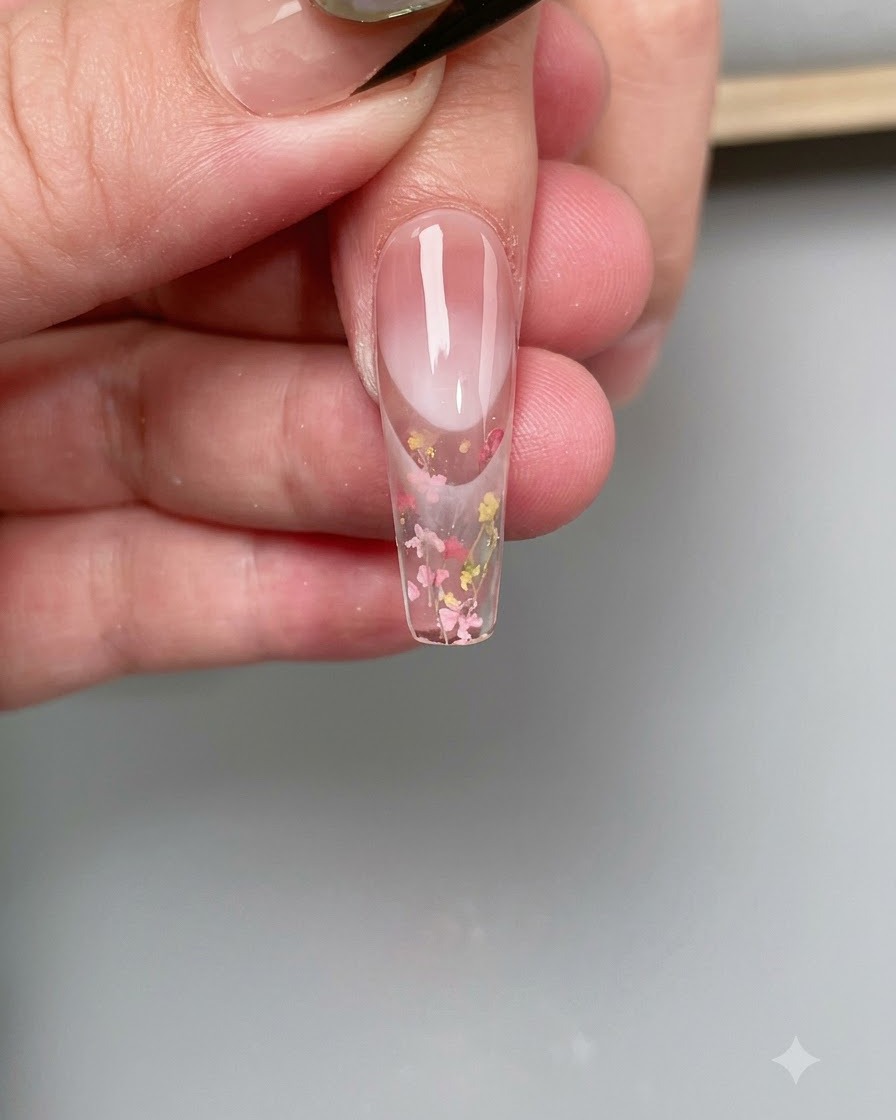 Un pennello sottile applica la base coat trasparente sulla superficie di una tip per unghie trasparente.
