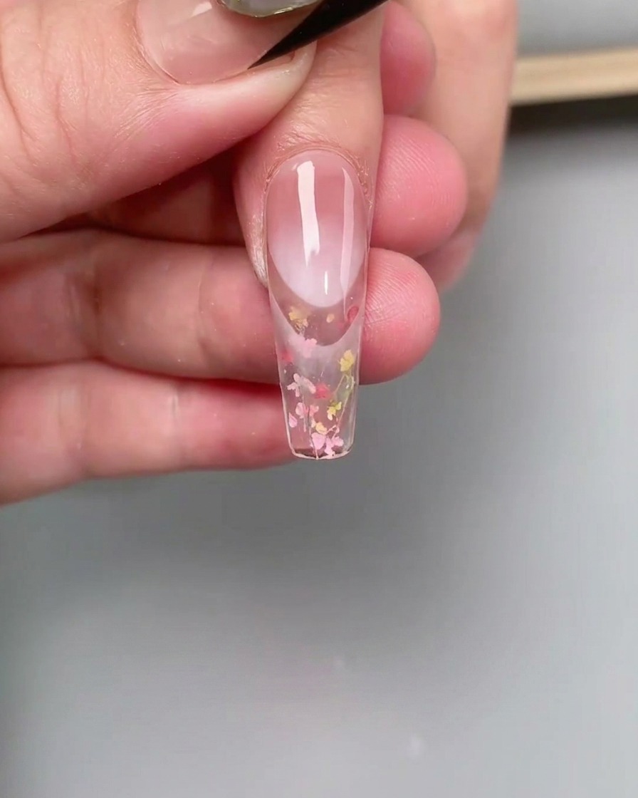 Un pennello liner sottile sfuma lo smalto gel rosa nella zona delle cuticole di ununghia per creare un effetto degradè.