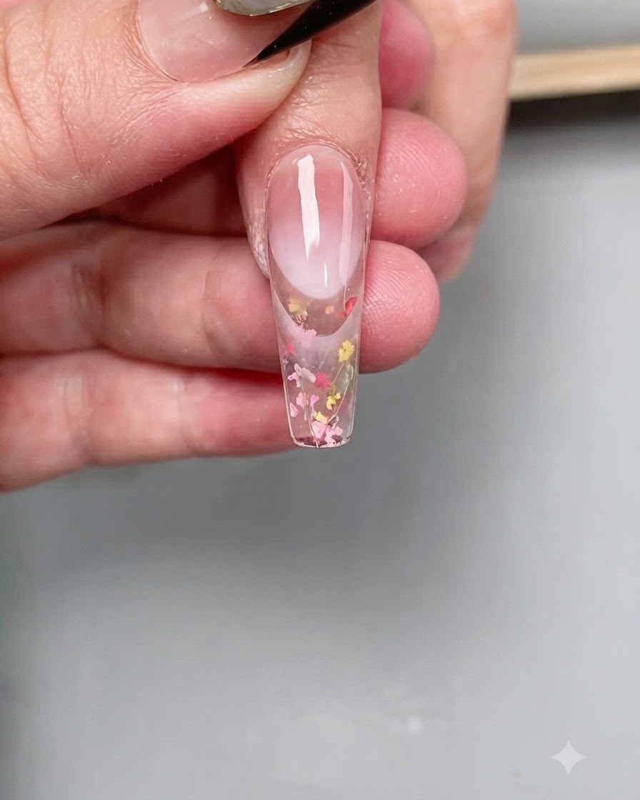 Un pennello sottile per nail art applica un top coat diamantato trasparente con precisione sulla punta di ununghia lunga a bara.