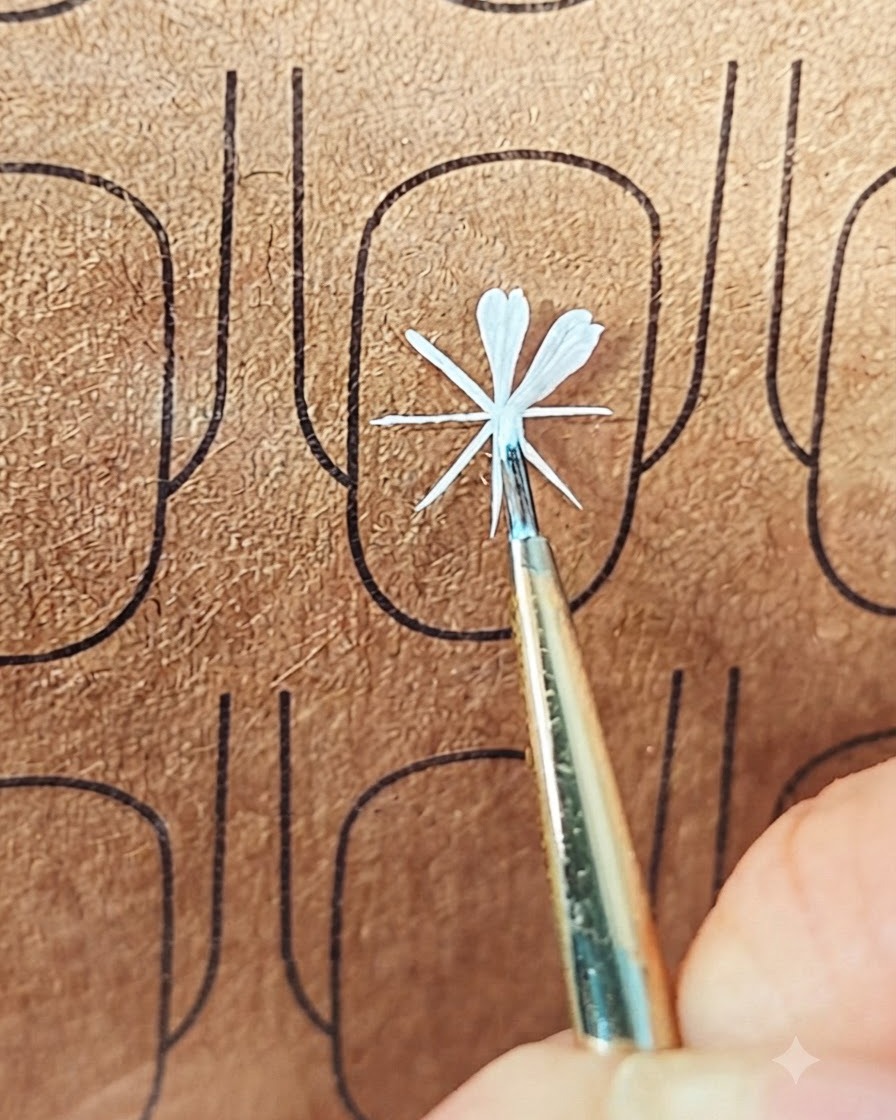 Un pennello fine per nail art che posiziona il gel bianco per formare un secondo petalo su una tavoletta di prova.