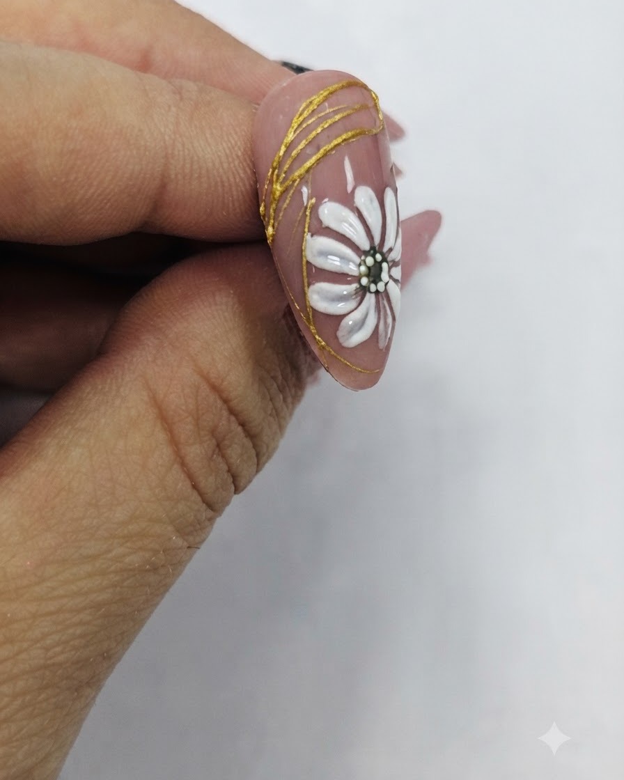 Un pennello che applica un top coat trasparente lucido su un design per unghie finito con margherita bianca e accenti dorati.