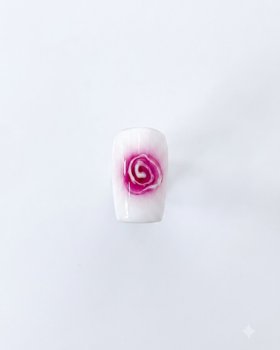 Un design di nail art con rosa sfumata completato, con centro rosso e petali bianchi morbidi in espansione su sfondo bianco.