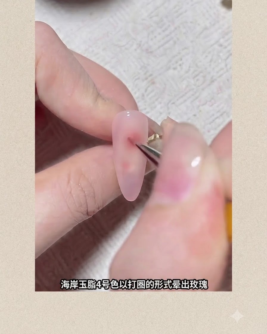 Un pennello fine per nail art disegna un punto di pigmento circolare rossastro su ununghia rivestita in gel rosa per formare un fiore in blooming.