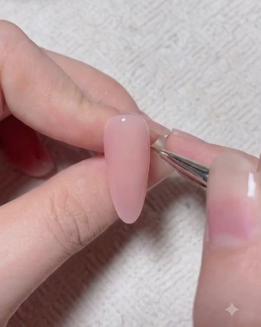 Un pennello da dettaglio applica un pigmento daccento più scuro sulla superficie di ununghia in gel rosa.
