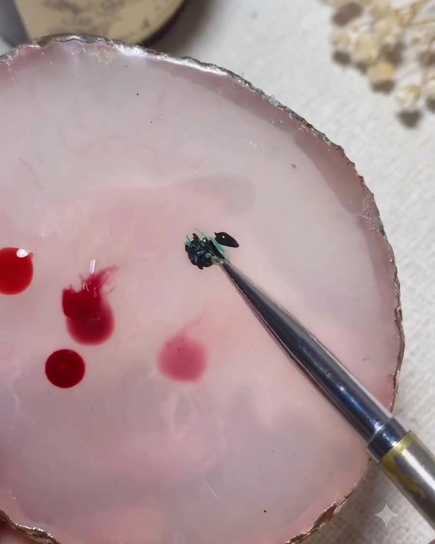 Uno strumento di miscelazione mescola colori in gel verde e nero insieme su una tavolozza di marmo rosa.