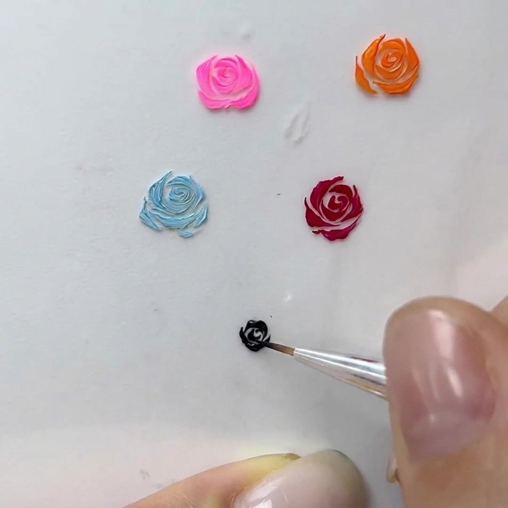 Una vista macro di unartista delle unghie che aggiunge sottili tratti curvi al bordo di una rosa in gel nera.