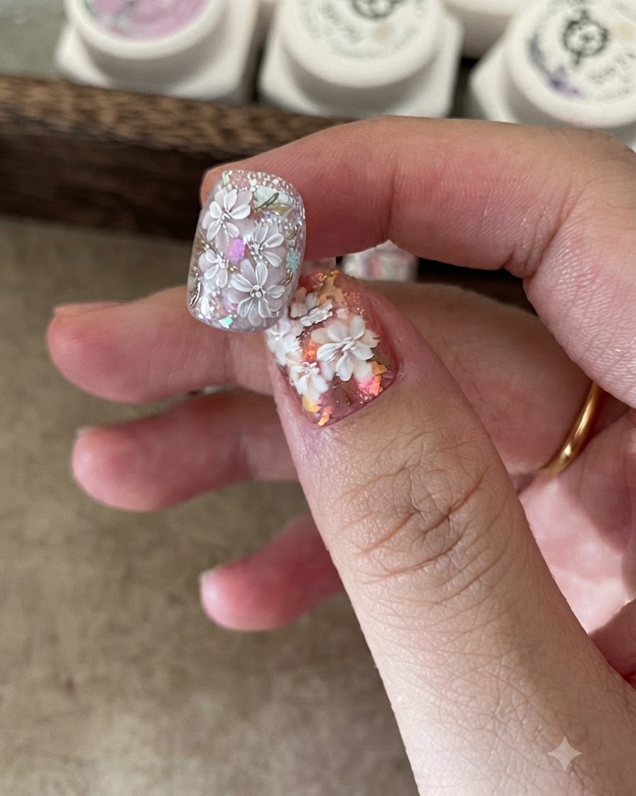Un pennellino posiziona fiocchi di foil iridescente su una base adesiva per unghie.