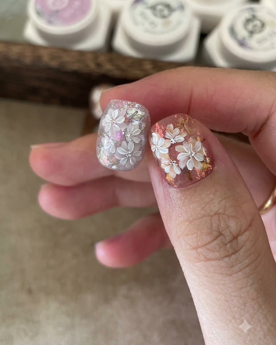 Primo piano di una pinzetta che posiziona fiocchi di foil iridescente su una base in gel appiccicosa.
