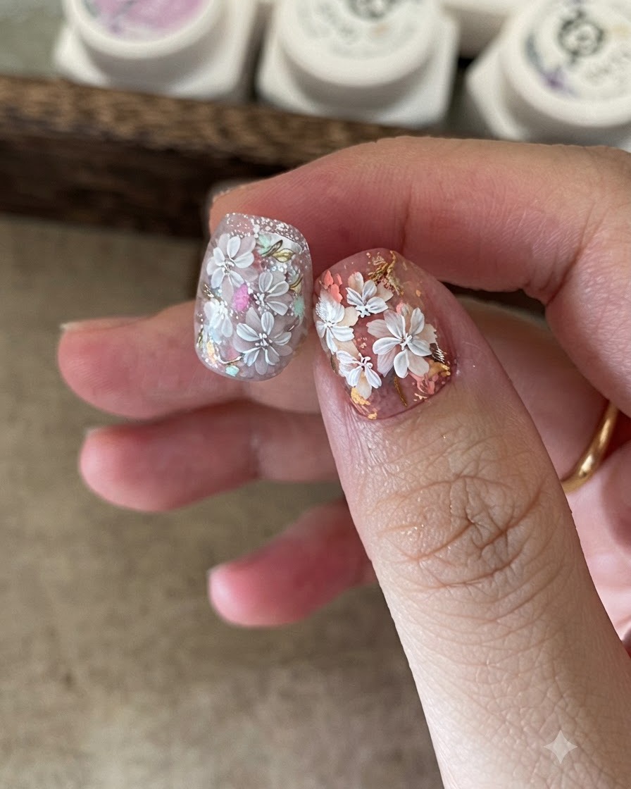 Primo piano di unonicotecnica che utilizza una spugnetta per applicare gel colorato al centro della nail art floreale bianca.