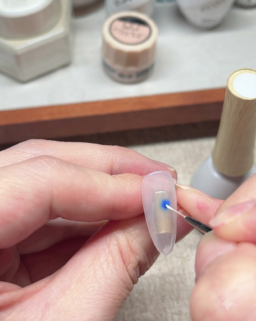 Un pennello liner sottile che interagisce con una goccia blu di smalto gel su ununghia per avviare leffetto blooming.