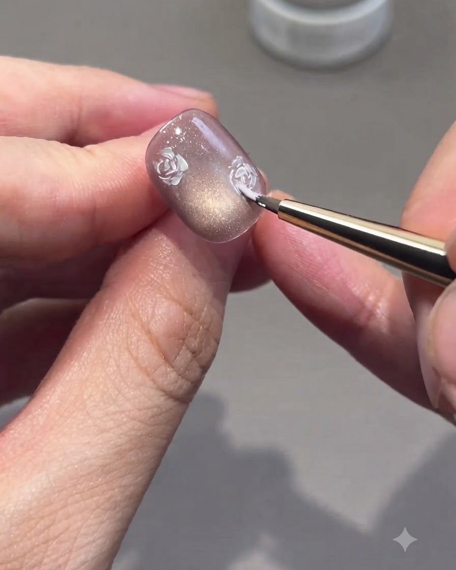 Un pennello fine che riempie i contorni delle rose con sfumature di gel rosa su ununghia.