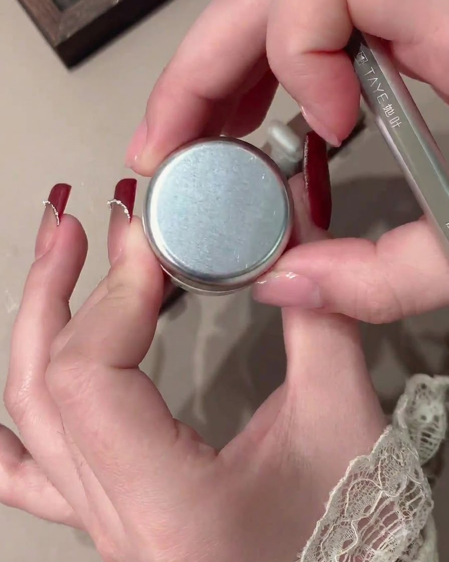 Un pennello applica il gel velluto rosso su una tip per unghie trasparente.