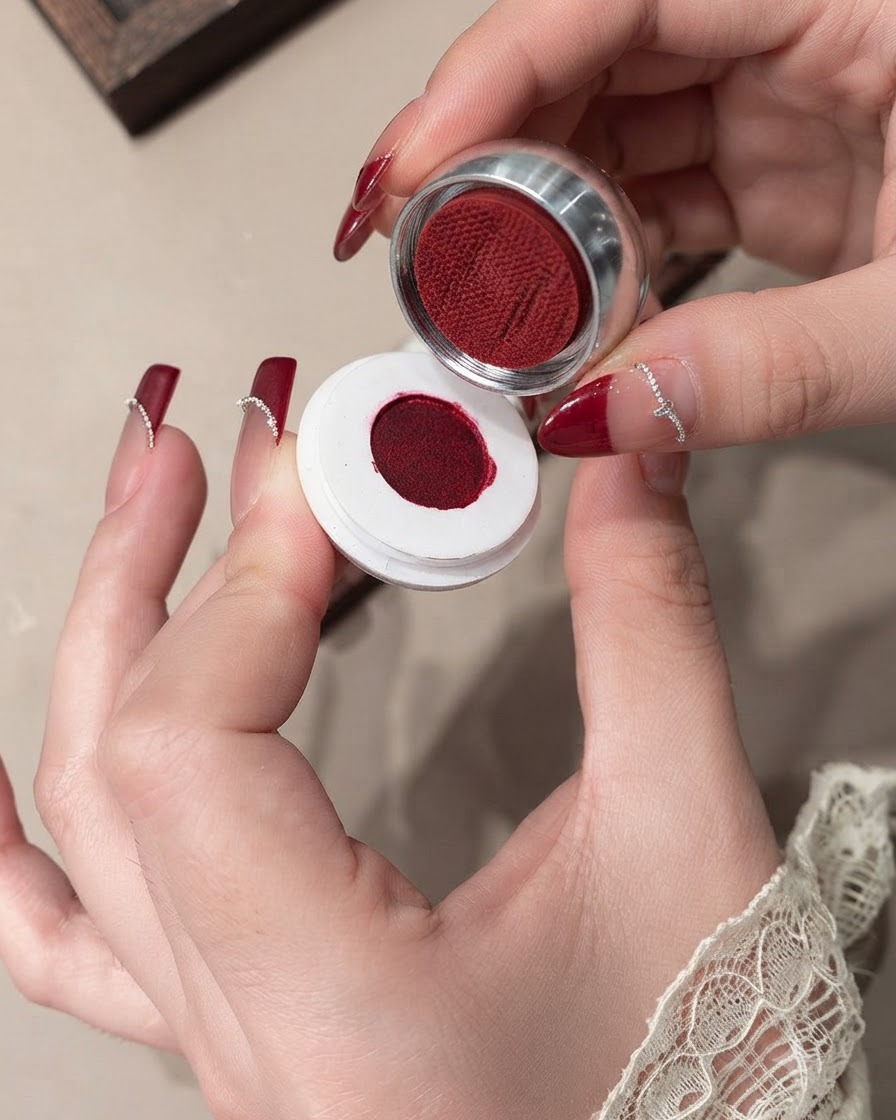 Primo piano di un pennello che livella il gel velluto rosso su ununghia.