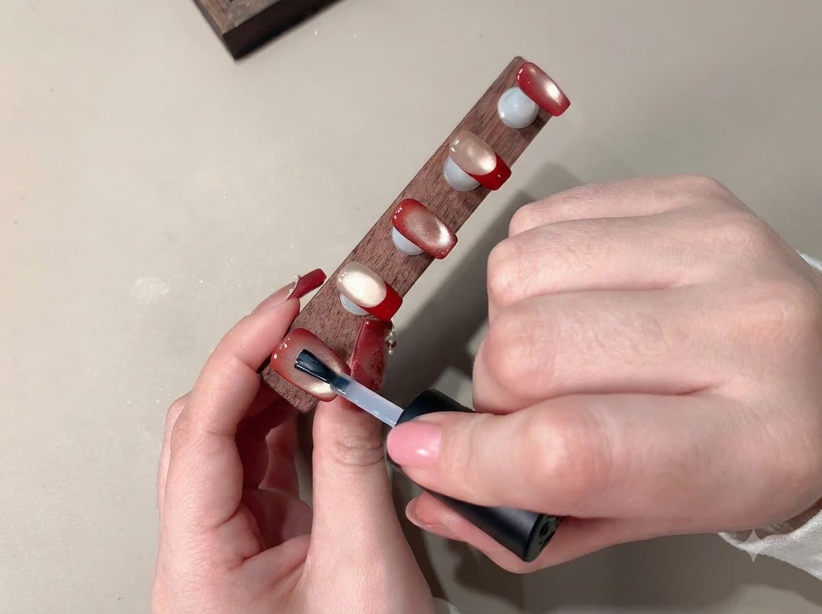 Un pennello applica un top coat trasparente per sigillare la nail art finita.