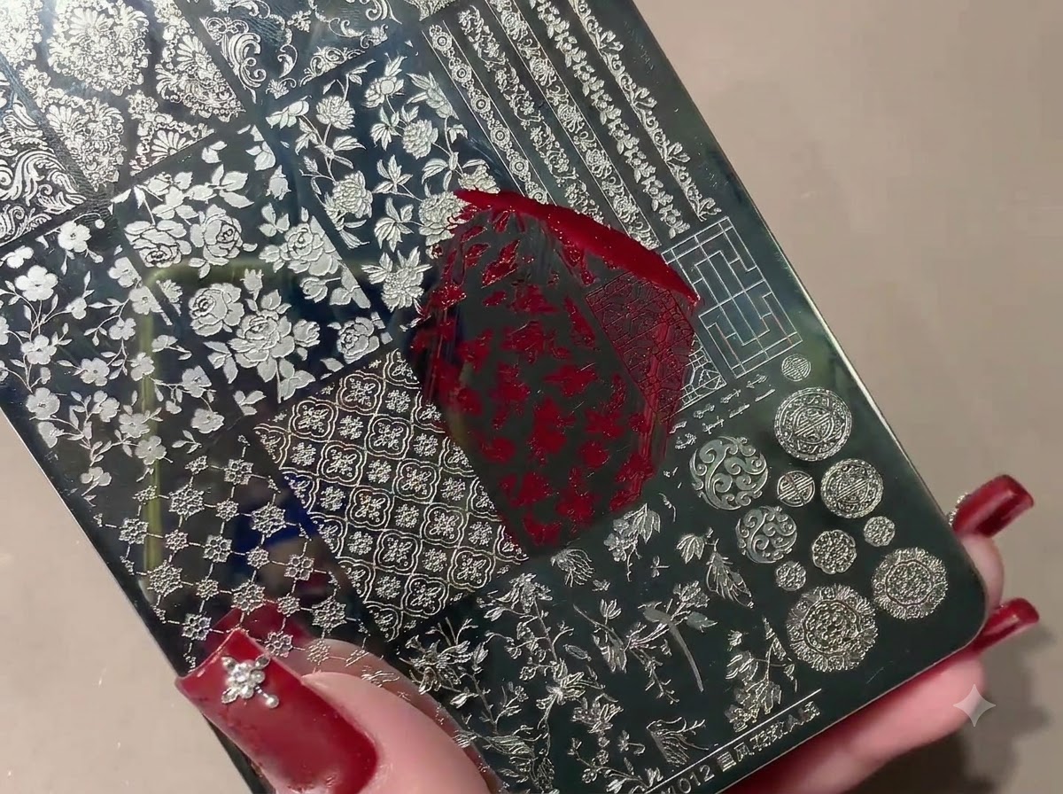 Un timbro in silicone preleva un motivo stampato in rosso da una piastra di stamping in metallo.