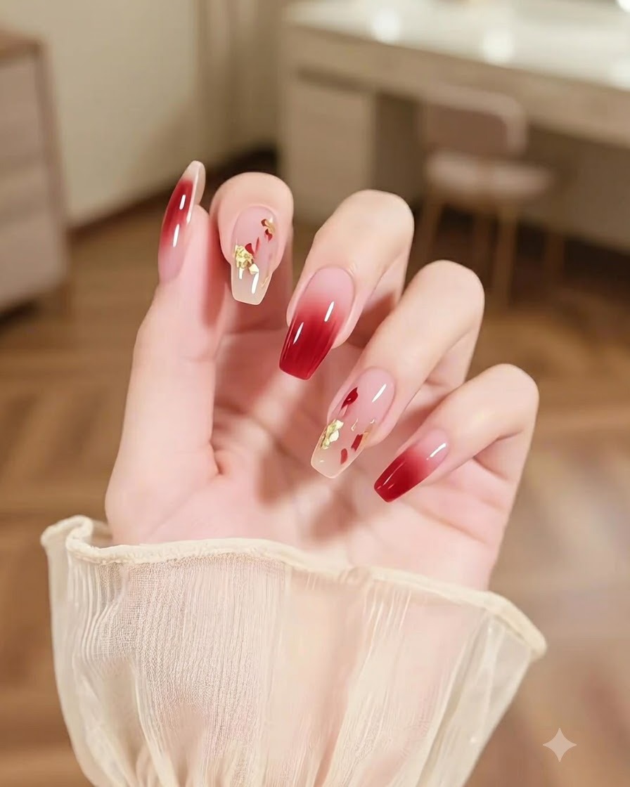 Un primo piano di una mano con ununghia accentata da pennellate multicolore astratte e brillantini dorati accanto a unghie ombré borgogna.